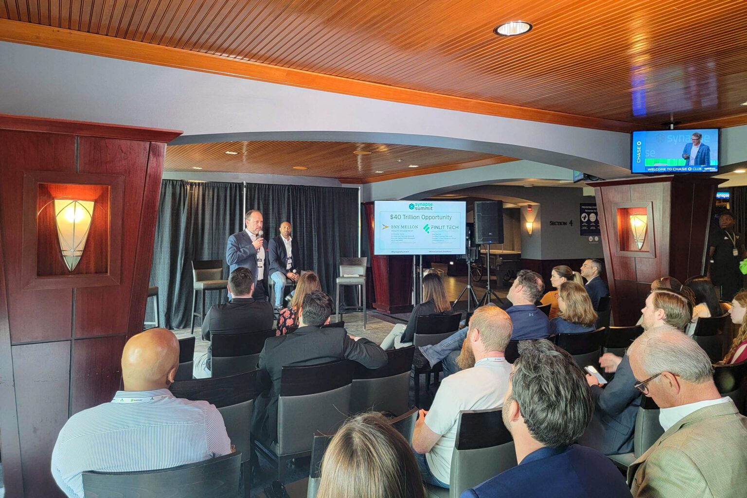 Speaker at a live event managed by DCE Productions on stage speaking to crowd with presentation behind him