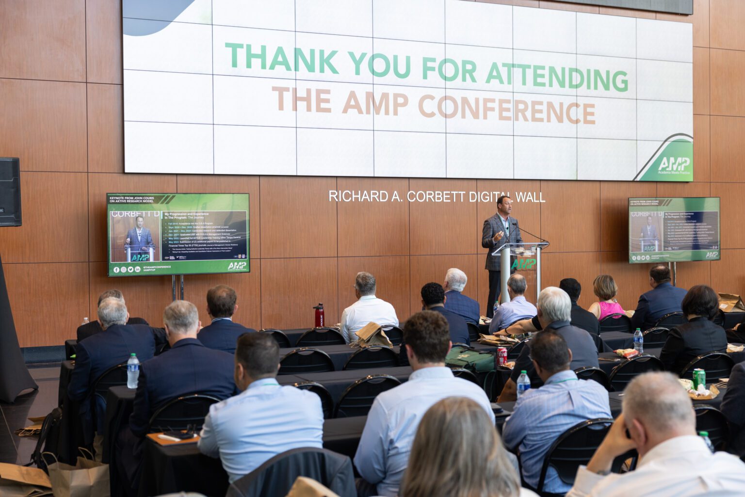 AMP Conference stage and crowd with the Richard A. Corbett Digital Wall as background