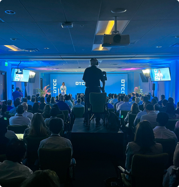 Hybrid live and virtual event being filmed by a member of DCE Productions standing on a platform in the center of the room