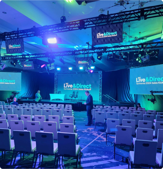Live & Direct event AV setup with overhead lighting, large screens and advanced video production