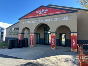 FL Agricultural Hall of Fame Hologram Theater entrance at the 2026 Florida State Fair, featuring explore discover learn play signage by DCE Productions